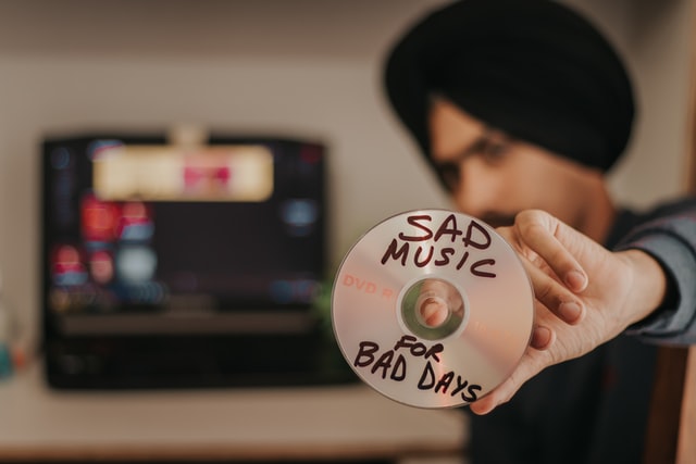 Shame. A man in a turban holding CD sad music by dollar gill on unsplash